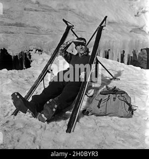 Un Skiurlauber hat sich aus seinen Sitz und einen skieur gebaut macht eine Pause, Deutschland 1930 er Jahre. Un tourisme de ski construit un siège de ses skis et d'avoir une pause maintenant, l'Allemagne des années 1930. Banque D'Images