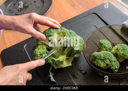 Préparer et trancher des brocolis verts (Brassica oleracea) à la main pour le déjeuner dans la cuisine, vue d'en haut Banque D'Images