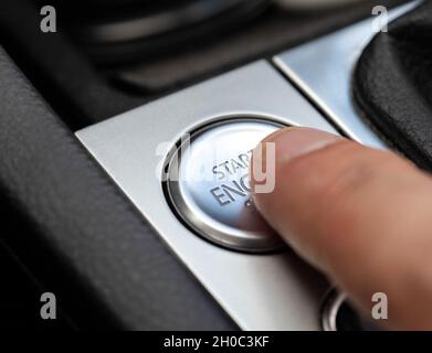 Le doigt de l'homme appuie sur le bouton de voiture moderne pour démarrer la voiture, macro.Technologie Banque D'Images