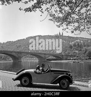 Ein junges Paar einem Cabrio à Würzburg, Deutschland 1930 er Jahre. Un jeune couple au volant dans un convertible, à la rive du fleuve Main à Würzburg, Allemagne 1930. Banque D'Images