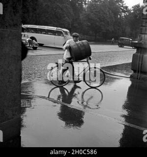 Ein Mann einFas transportiert auf seinem Fahrrad durch den Regen, Deutschland 1930er Jahre. Un homme transportant un canon sur son vélo à travers la pluie, Allemagne 1930. Banque D'Images