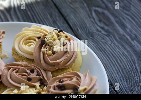 Gâteau éponge décoré de crème et de gouttes de chocolat.Sont disposés sur un plateau.Ils se tiennent sur une surface en planches de pin.Gros plan. Banque D'Images