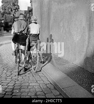 Hitlerjunge ein und ein Mädel BDM auf Ihren Fahrrädern in einer Gasse à Braunschweig, Deutschland 1930 er Jahre. Une jeunesse d'Hitler et une fille BDM sur leur bicyclette dans une ruelle de Braunschweig, Allemagne 1930. Banque D'Images