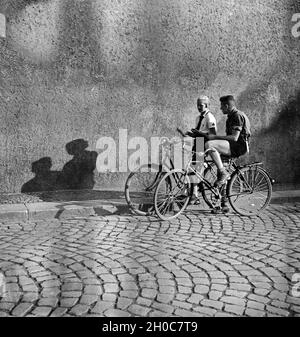 Hitlerjunge ein und ein Mädel BDM auf Ihren Fahrrädern in einer Gasse à Braunschweig, Deutschland 1930 er Jahre. Une jeunesse d'Hitler et une fille BDM sur leur bicyclette dans une ruelle de Braunschweig, Allemagne 1930. Banque D'Images