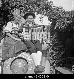 Ein Paar dans der Tracht der Wachau sitzt auf dem Kofferraum von Opel Olympia und macht Musik auf einem Akkordeon, Österreich 1930 er Jahre. Un jeune couple wearing tableau de zone de Wachau assis à une Opel Olympia voiture et faire de la musique avec un accordéon, Autriche 1930. Banque D'Images