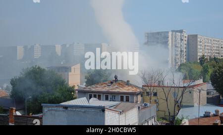 Pompiers sur le toit de la maison en feu essayant d'éteindre des flammes.Équipe de pompiers du service de lutte contre les incendies avec camion et équipement mettant le feu sur le bâtiment avec de l'eau. Banque D'Images