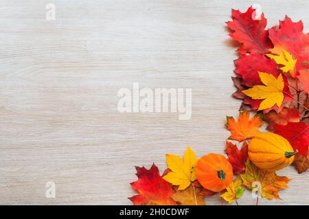 Composition d'automne avec feuilles colorées et citrouille sur fond de bois.Composition d'automne à plat avec espace de copie. Banque D'Images