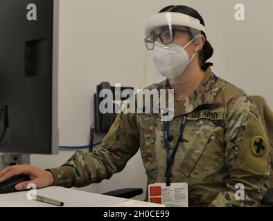 Illinois Army National Guard Medic SPC.Lynnette Banvelos, d'Addison, Illinois, entre les réponses aux questions de dépistage de la vaccination dans le réseau du département de santé du comté de Cook avant d'administrer un vaccin à un membre de la communauté locale du centre de santé North Riverside de Cook County Health.Les médecins de l'armée reçoivent environ quatre mois de formation intensive dans les tâches médicales à fort Sam Houston, Texas, y compris l'administration de vaccins.Après leur formation initiale, les médecins sont tenus de certifier à nouveau périodiquement.Dans l'Illinois, les médecins sont certifiés par l'État au niveau de l'EMT, mais le Banque D'Images