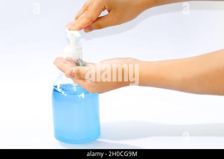 Insertion du gel désinfectant pour les mains dans la paume à partir d'un flacon à pompe, du gel bleu, du fond blanc et de l'espace de copie Banque D'Images