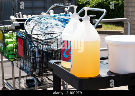 Un cours de gym a deux grandes bouteilles de désinfectant pour les mains à côté des raquettes de tennis et des balles à utiliser avant et après. Banque D'Images