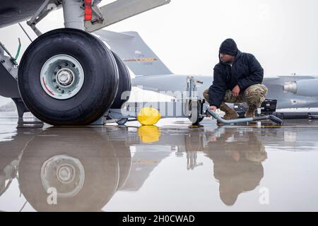 Le principal Airman Elijah Turner, chef d'équipage du 911e Escadron de maintenance d'aéronefs, abaisse un cric de 35 tonnes du train d'atterrissage d'un C-17 Globemaster III à la station de réserve aérienne de l'aéroport international de Pittsburgh, en Pennsylvanie, le 26 janvier 2021.Les agents de maintenance effectuent l'entretien de routine du train d'atterrissage de l'avion pour s'assurer que la mission est prête. Banque D'Images