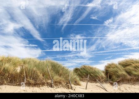 Dunes couvertes de végétation avec un ciel bleu, des nuages et des rayons blancs Banque D'Images