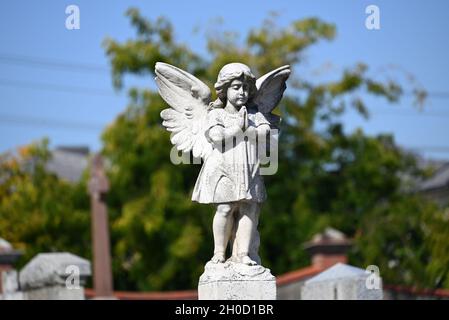 Sculpture d'un chérubin de prière dans un cimetière pendant une journée ensoleillée Banque D'Images