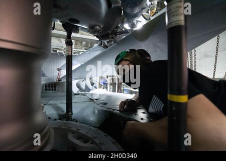 210128-N-WQ732-4004 OCÉAN ATLANTIQUE (JANV28, 2021) – l’officier de vaisseau compagnon de l’Aviation Machiniste de 2e classe Marcus Molinar, d’Arlington, Texas, effectue un contrôle de la corrosion sur un Faucon de mer MH60-R affecté à l’Escadron maritime d’hélicoptères « renards de marais » (HMS) 74 à bord du croiseur de missiles guidés de classe Ticonderoga USS Monterey (CG 61), le 28 janvier 2021.Monterey est en cours dans l'océan Atlantique dans le cadre du Groupe de grève des transporteurs Dwight D. Eisenhower. Banque D'Images