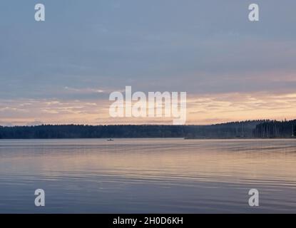 Pêcheur en bateau tôt le matin sur le lac Lipno dans les montagnes Sumava, République Tchèque Banque D'Images