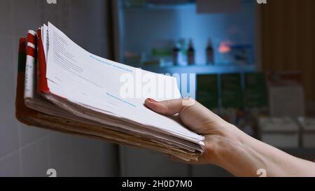Infirmière tenant la carte avec les résultats de l'examen.Gros plan de l'infirmière donnant les résultats de l'examen et des tests sur fond sombre de l'hôpital.Résultats Banque D'Images