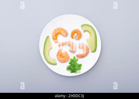 Assiette en céramique blanche avec fruits de mer, crevettes cuites, avocat.Image conceptuelle minimale sur le régime alimentaire, le mode de vie sain.Vue de dessus. Banque D'Images