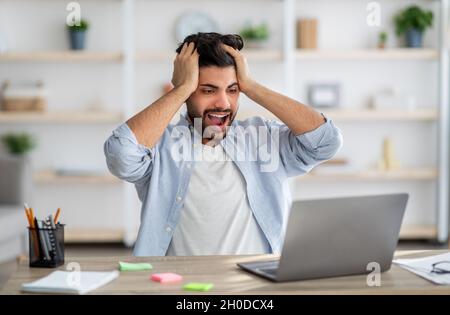 OMG, mauvaise nouvelle.Un homme arabe décontentant criait, regardant un ordinateur portable, ayant des problèmes avec un ordinateur ou un logiciel Banque D'Images