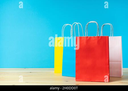 Sacs en papier multicolores pour faire du shopping sur la table et arrière-plan coloré avec meth pour le texte. Banque D'Images