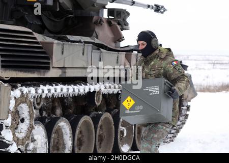 Armée roumaine le soldat Transylvanien Gepard apporte une boîte à munitions à son véhicule lors d'un tir de combat conjoint du système de défense aérienne Gepard le 2 février 2021 à la zone d'entraînement de Bemowo Piskie, en Pologne. Banque D'Images