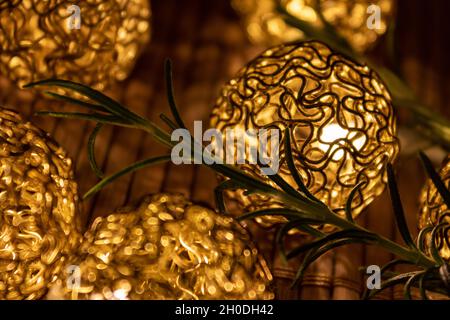 boules de noël dorées lumineuses avec branche de sapin sur table en bois, gros plan. décor élégant et festif Banque D'Images