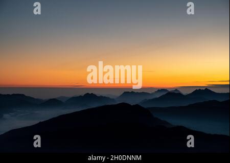 quelques instants avant le lever du soleil sur le sommet d'une montagne qui donne sur les sommets des alpes bavaroises et autrichiennes avec du brouillard dans les vallées Banque D'Images