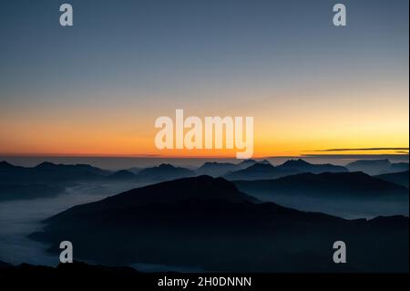 quelques instants avant le lever du soleil sur le sommet d'une montagne qui donne sur les sommets des alpes bavaroises et autrichiennes avec du brouillard dans les vallées Banque D'Images