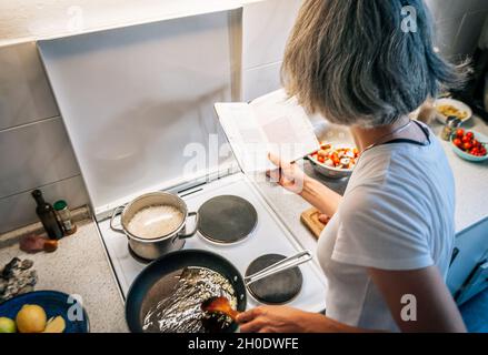 Une femme étudie la recette et cuisine dans la cuisine à la maison Banque D'Images