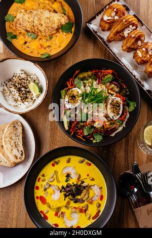 La table est servie avec une variété de plats asiatiques.Soupe. Salade. Plat chaud. Dessert. Banque D'Images