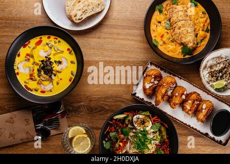 La table est servie avec une variété de plats asiatiques.Soupe. Salade. Plat chaud. Dessert. Banque D'Images