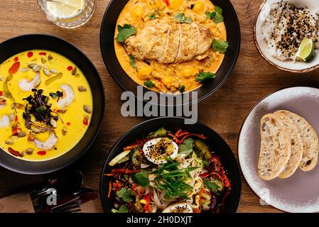 La table est servie avec une variété de plats asiatiques.Soupe. Salade. Plat chaud. Dessert. Banque D'Images