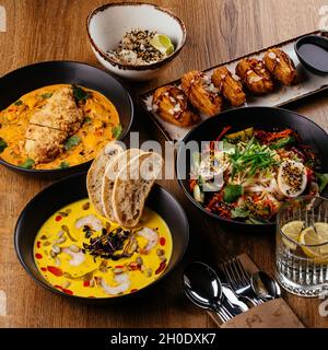 La table est servie avec une variété de plats asiatiques.Soupe. Salade. Plat chaud. Dessert. Banque D'Images