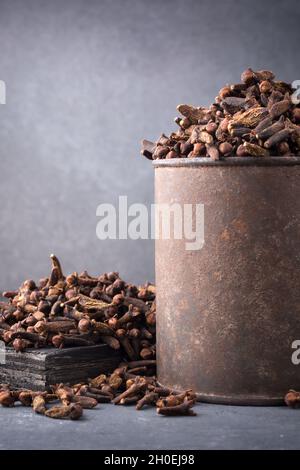 séchez les clous de girofle dans une vieille tasse avec des clous de girofle éparpillés, des épices aromatiques et des herbes, vue rapprochée du concept de la vie still Banque D'Images