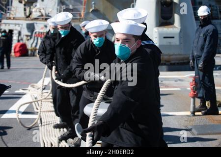 210217-N-QD512-1305 NORFOLK (FÉV17, 2021) les marins montent en ligne d'amarrage avant de quitter la base navale de Norfolk à bord du destroyer à missiles guidés de la classe Arleigh Burke USS Mitscher (DDG 57) le 17 février 2021.Mitscher opère dans l'océan Atlantique à l'appui d'opérations navales visant à maintenir la stabilité et la sécurité maritimes afin d'assurer l'accès, de décourager l'agression et de défendre les intérêts américains, alliés et partenaires. Banque D'Images