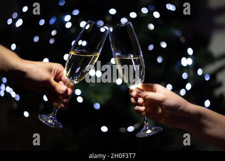 Fêtez Noël à la maison, couple clinking verres avec champagne et de tenir des sparkers sur fond d'arbre de noël, gros plan. Banque D'Images