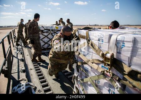 Les aviateurs et les soldats de l'Armée de l'Air des États-Unis déchargent des palettes d'eau embouteillée, le 21 février 2021, à la base interarmées de San Antonio-Kelly Field, Texas.La base commune de San Antonio a fourni une aide d'urgence aux autorités et organismes locaux afin d'assurer la sécurité de la communauté pendant et après la tempête hivernale. Banque D'Images