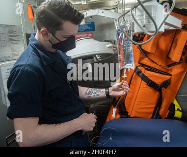 210221-N-FD648-1065 OCÉAN ATLANTIQUE (FÉV21, 2021) -- l'hôpital Corpsman Seaman Chad Backman, d'Utica, New York, teste le saignement d'un sac I.V. à bord du destroyer de missile guidé de classe Arleigh Burke USS Mahan (DDG 72) le 21 février 2021.Mahan opère dans l'océan Atlantique à l'appui d'opérations navales visant à maintenir la stabilité et la sécurité maritimes afin d'assurer l'accès, de décourager l'agression et de défendre les intérêts des États-Unis, des alliés et des partenaires. Banque D'Images