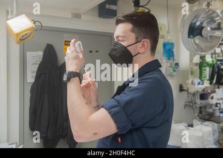 210221-N-FD648-1050 OCÉAN ATLANTIQUE (FÉV21, 2021) – l'hôpital Corpsman Seaman Chad Backman, d'Utica, New York, remplit une seringue à bord du destroyer à missiles guidés de classe Arleigh Burke USS Mahan (DDG 72) le 21 février 2021.Mahan opère dans l'océan Atlantique à l'appui d'opérations navales visant à maintenir la stabilité et la sécurité maritimes afin d'assurer l'accès, de décourager l'agression et de défendre les intérêts des États-Unis, des alliés et des partenaires. Banque D'Images