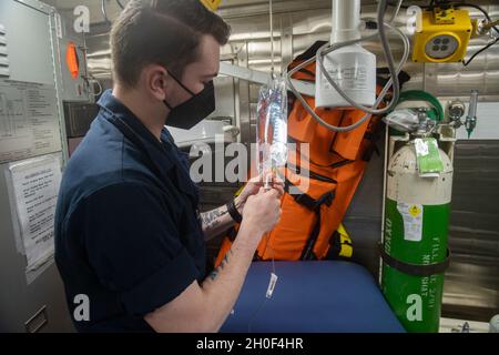 210221-N-FD648-1063 OCÉAN ATLANTIQUE (FÉV21, 2021) -- l'hôpital Corpsman Seaman Chad Backman, d'Utica, New York, prépare un sac I.V. à bord du destroyer de missile guidé de classe Arleigh Burke USS Mahan (DDG 72) le 21 février 2021.Mahan opère dans l'océan Atlantique à l'appui d'opérations navales visant à maintenir la stabilité et la sécurité maritimes afin d'assurer l'accès, de décourager l'agression et de défendre les intérêts des États-Unis, des alliés et des partenaires. Banque D'Images