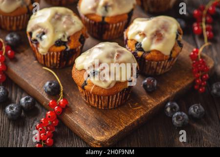 Muffins faits maison aux raisins de Corinthe rouges et aux bleuets, recouverts de garniture au chocolat blanc. Banque D'Images
