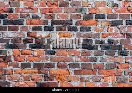 Fragment d'une partie du mur d'une maison faite de vieilles briques rouges et brunes altérées pour servir de fond. Banque D'Images