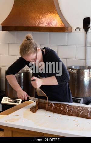 Une femme qui fabrique du fudge, un type de confiserie, à l'intérieur de la boutique de Roly Fudge Pantry, Looe, Cornwall, Royaume-Uni Banque D'Images