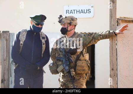 Un soldat des États-Unis affecté à la 64e Compagnie militaire, 91e Bataillon de génie de brigade, 1re Division de cavalerie discute des opérations de sécurité avec la police de ville simulée pendant la résolution XV combinée à la zone d'entraînement de Hohenfels, Hohenfels, Allemagne, le 27 février 2021.Combined Resolve XV est un exercice multinational dirigé par le département de l'Armée de terre conçu pour construire l'équipe de combat de la 1re Brigade blindée, la préparation de la 1re Division de Cavalry et améliorer l'interopérabilité avec les forces alliées pour combattre et gagner contre tout adversaire. Banque D'Images