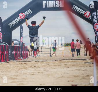 Un participant à la course de Spartan d'Okinawa célèbre son arrivée à Chura Sun Beach, Okinawa, Japon, le 27 février 2021.Okinawa a organisé sa toute première course Spartan, attirant plus de 2,000 concurrents pour se lancer dans des courses remplies de plus de 20 obstacles, notamment des haies, des chenilles basses dans le sable, des lancers de javelin, des haltérophilie et de l'escalade.Créée pour la première fois à Pittsfield, dans le Vermont, en 2010, la course Spartan attire maintenant plus de 1.5 millions de participants chaque année et est établie dans plus de 40 pays dans le monde entier. Banque D'Images