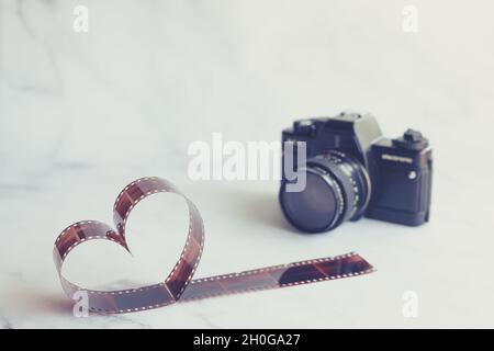 Film négatif en forme de coeur avec caméra de film Vintage sur fond de marbre Banque D'Images