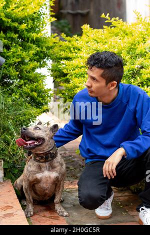 Jeune garçon adulte assis à côté de son animal de compagnie comme ils regardent tous les deux sur le côté. Photo verticale. Meilleurs amis. Banque D'Images