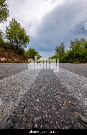 route de tarmac du point de vue bas regardant le long de la route à la disparition ou point de fuite dans la distance. vue de bas niveau de la route continuant dans la distance. Banque D'Images