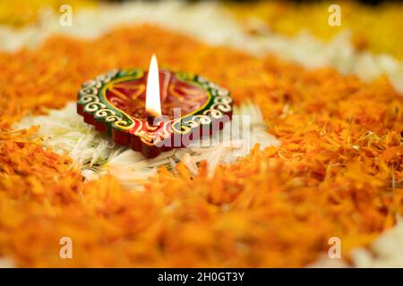 Diya de Clay fait à la main illuminé sur Floral Rangoli fait de fleurs Marigold avec bokeh en arrière-plan.Festival indien thème pour Diwali Pooja, Navratri Banque D'Images