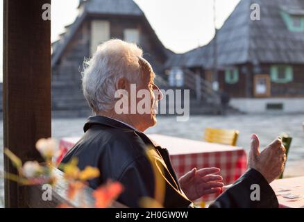 Vue arrière de l'homme senior assis au restaurant dans le vieux village Banque D'Images
