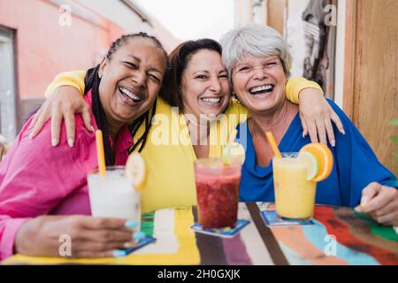 Femme sénior multiraciale ayant du plaisir à boire des smoothies sains au restaurant brunch - Focus sur le visage de femme du centre Banque D'Images